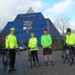 REF_1231b: photograph of four people with the blue Stockport pyramid building behind them. Thumbnail