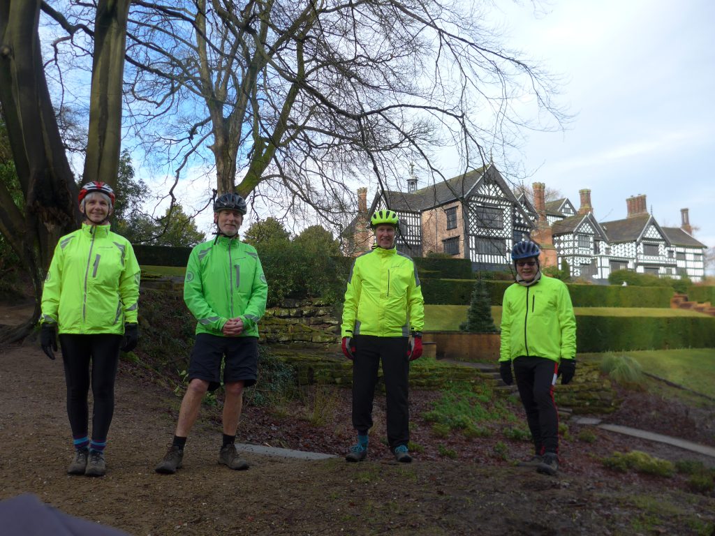 REF_1231c: photograph of four people with Bramall Hall behind them. 