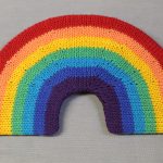 STOPM_2020_454a: knitted toy or souvenir of a rainbow; arch-shaped piece of flexible plastic, covered with a knitted rainbow in the colours of red, orange, yellow, green, turquoise, blue, and purple. Knitted by Linda Cornes Parker, who is a part of the group Knitting Friends in the Park. Thumbnail